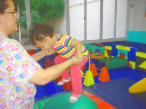Niña saltando en pelota con especialista